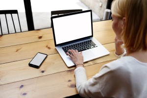 Female at laptop computer and smartphone with blank screen